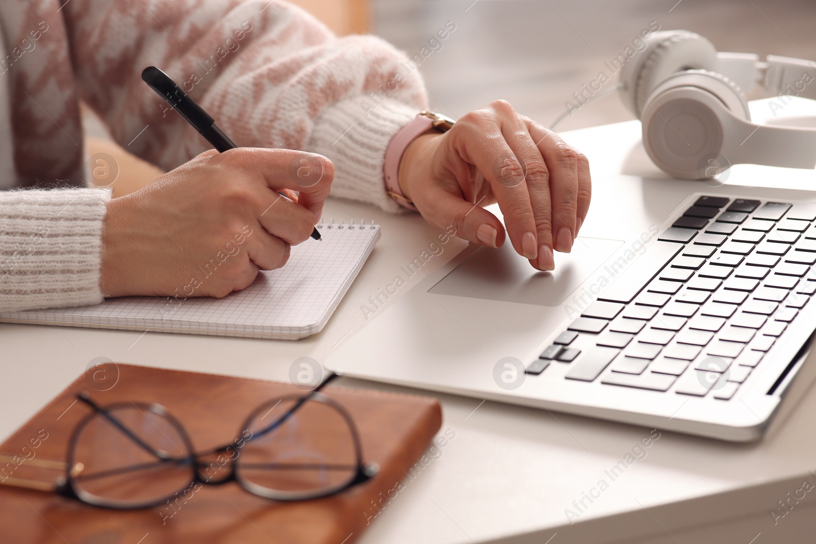 Photo of Woman with modern laptop learning at table indoors, closeup