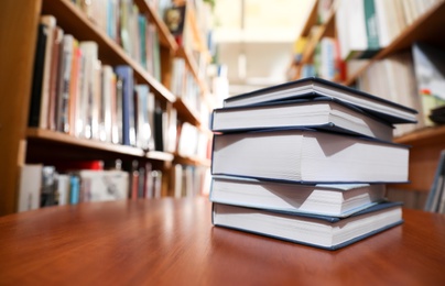 Photo of Stack of books on table in library. Space for text