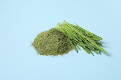 Pile of wheat grass powder and fresh sprouts on light blue table