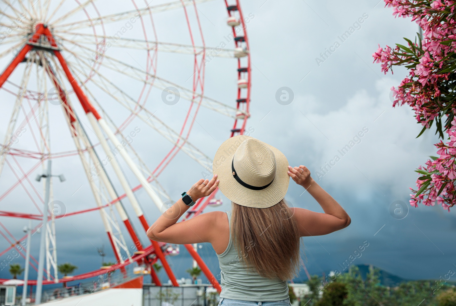 Photo of Woman near beautiful large Ferris wheel outdoors, back view. Space for text