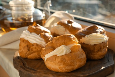 Delicious profiteroles filled with cream on window sill indoors, closeup