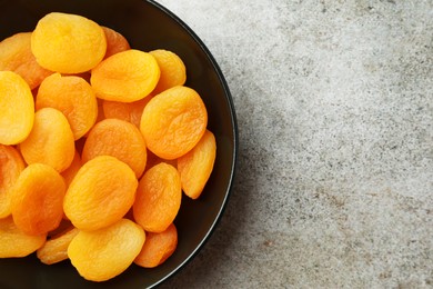 Photo of Plate of tasty apricots and space for text on grey table, top view. Dried fruits