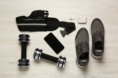 Photo of Flat lay composition with black waist bag on white wooden table
