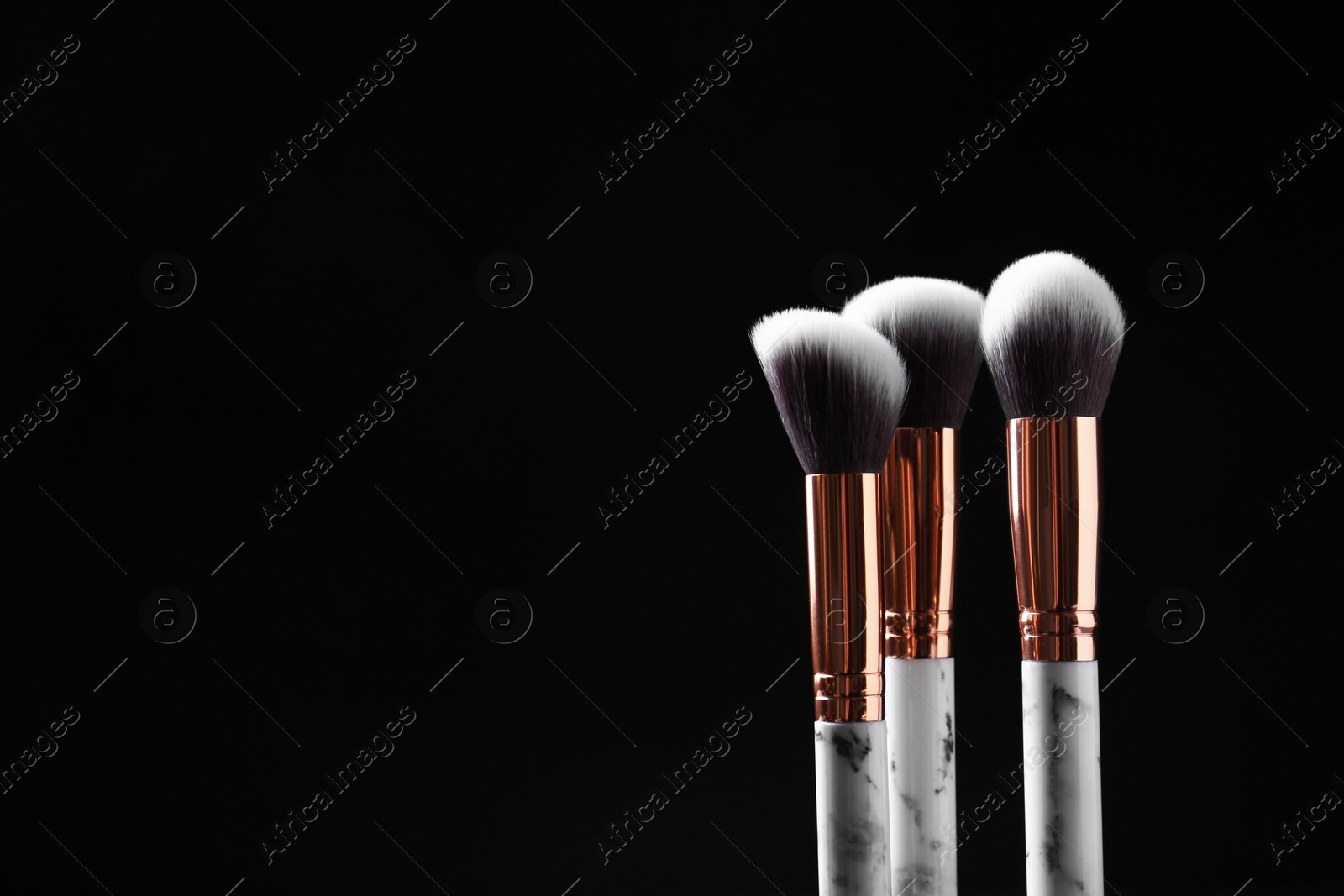 Photo of Set of makeup brushes against dark background. Space for text