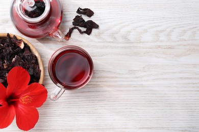 Delicious hibiscus tea and flowers on white wooden table, flat lay. Space for text