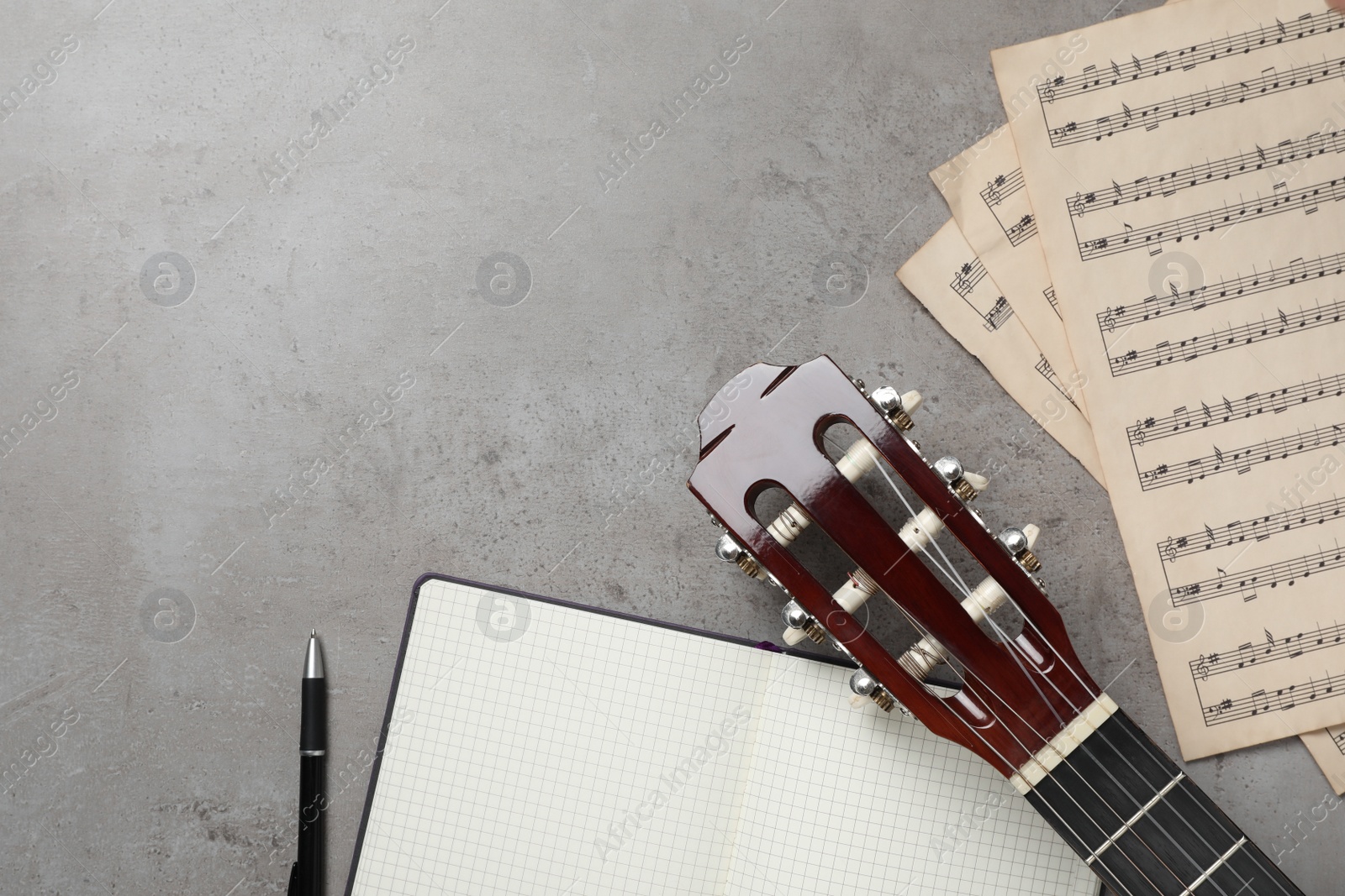 Photo of Composition with guitar and music notations on grey table, flat lay. Space for text