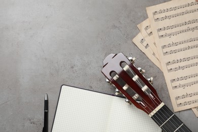 Photo of Composition with guitar and music notations on grey table, flat lay. Space for text