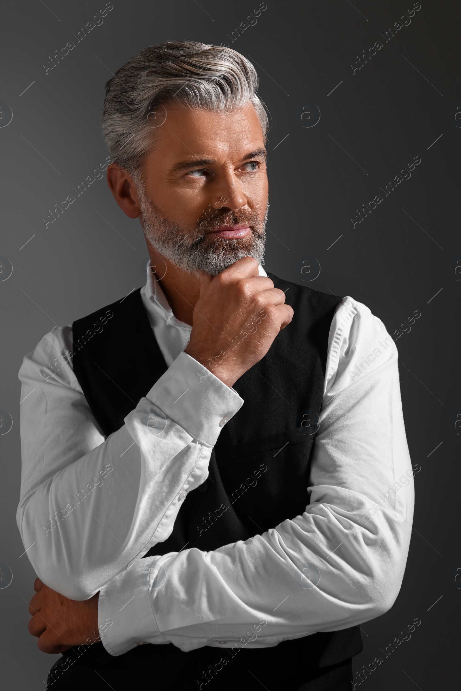 Photo of Portrait of confident man with beautiful hairstyle on dark background