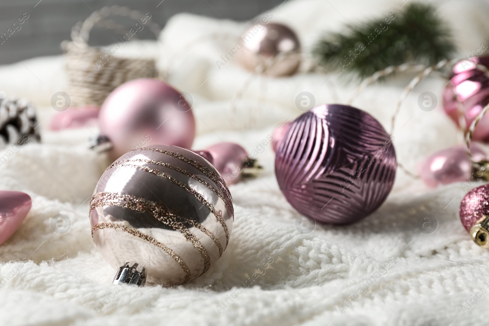 Photo of Beautiful pink Christmas baubles on white knitted plaid, closeup