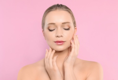 Portrait of young woman with beautiful face on pink background