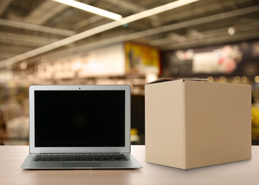 Image of Online selling. Laptop and parcel on table in store