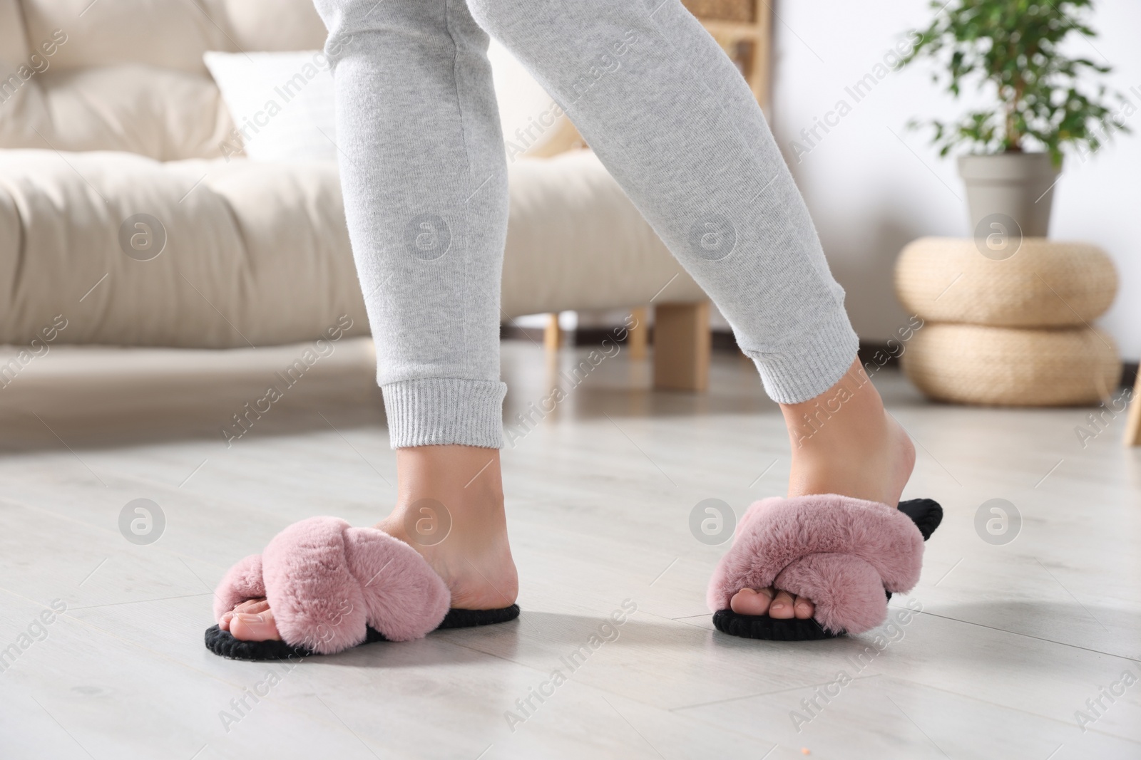 Photo of Woman wearing soft slippers at home, closeup of legs