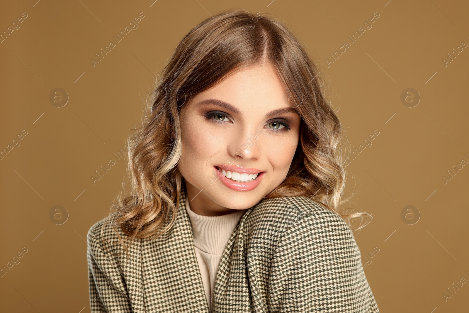 Photo of Portrait of young woman with beautiful makeup on light brown background