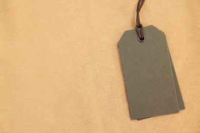 Photo of Cardboard tags on beige garment, top view. Space for text