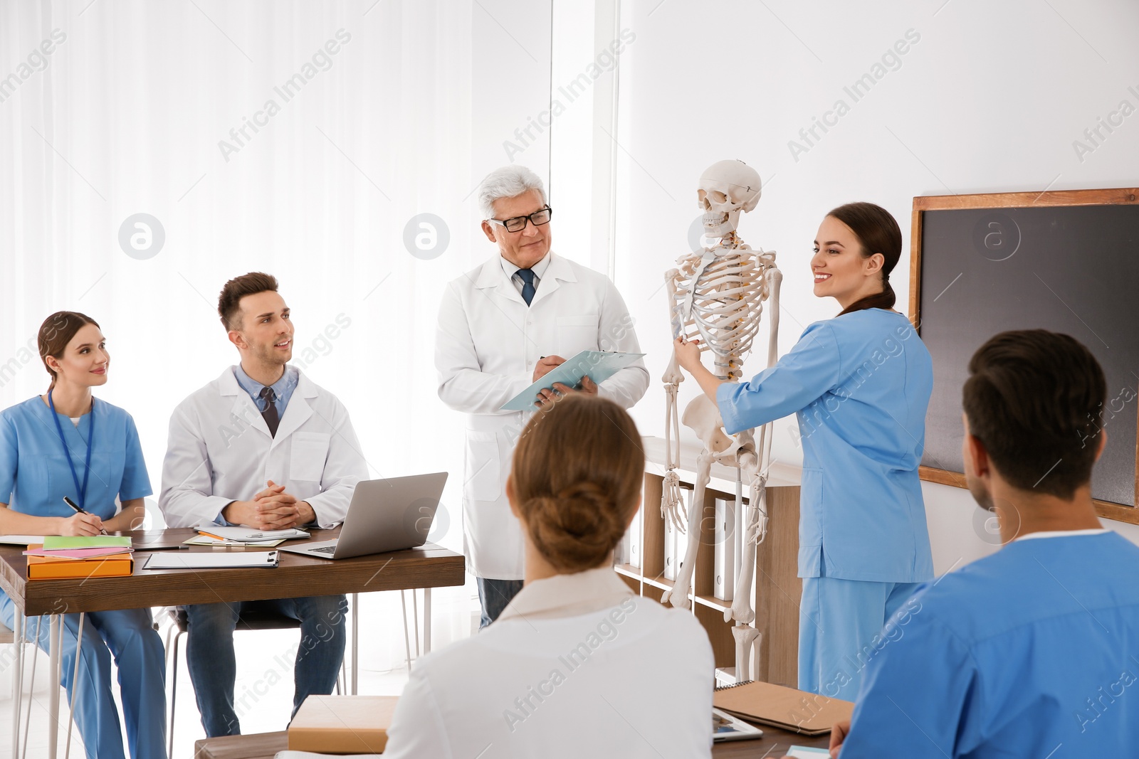 Photo of Medical students and professor studying human skeleton anatomy in classroom