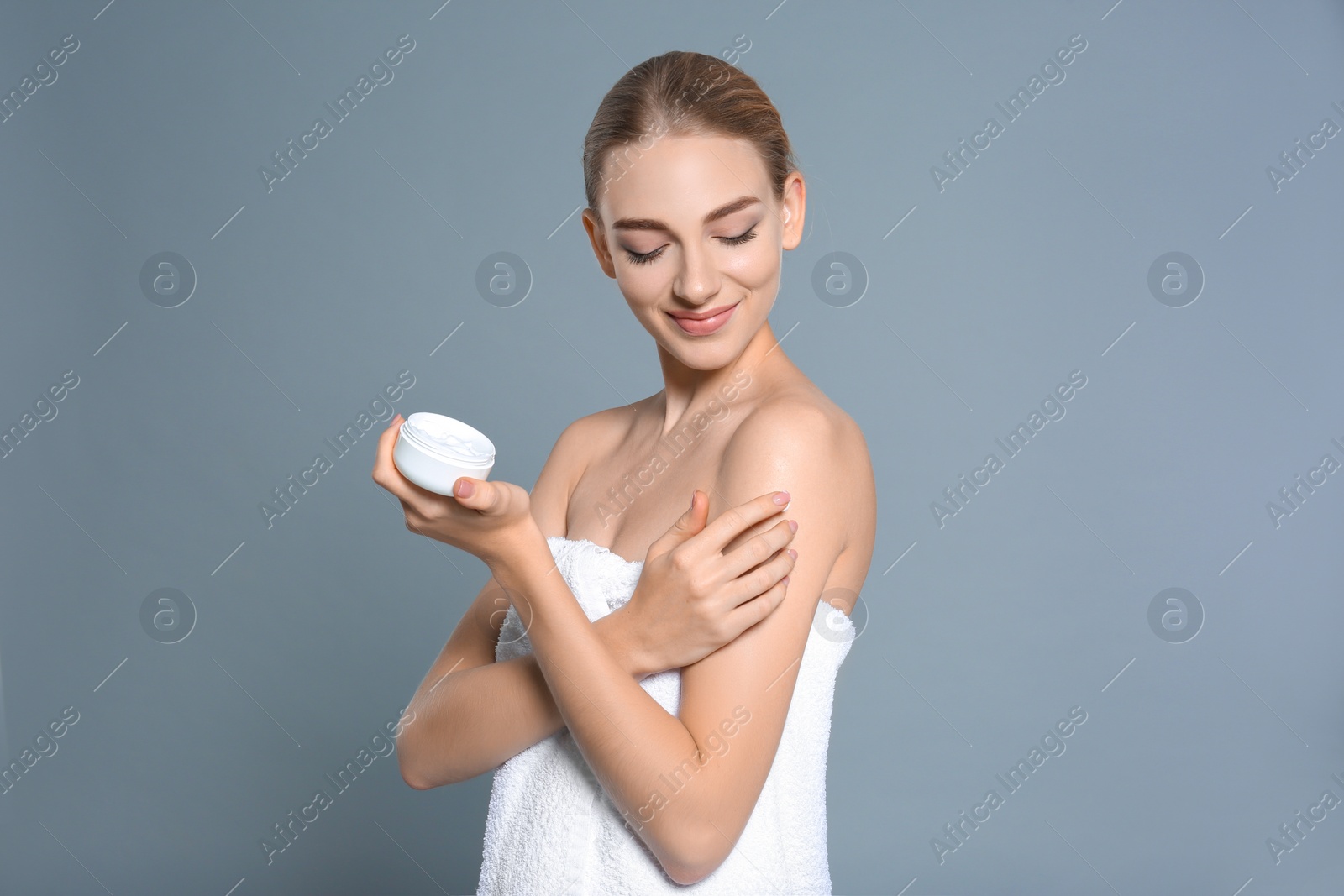 Photo of Young woman with jar of body cream on color background