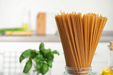 Uncooked buckwheat noodles in kitchen, closeup. Space for text