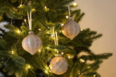 Photo of Christmas tree decorated with holiday baubles and fairy lights, closeup