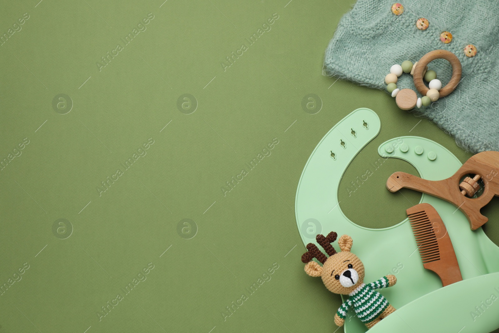 Photo of Flat lay composition with baby accessories and bib on green background, space for text