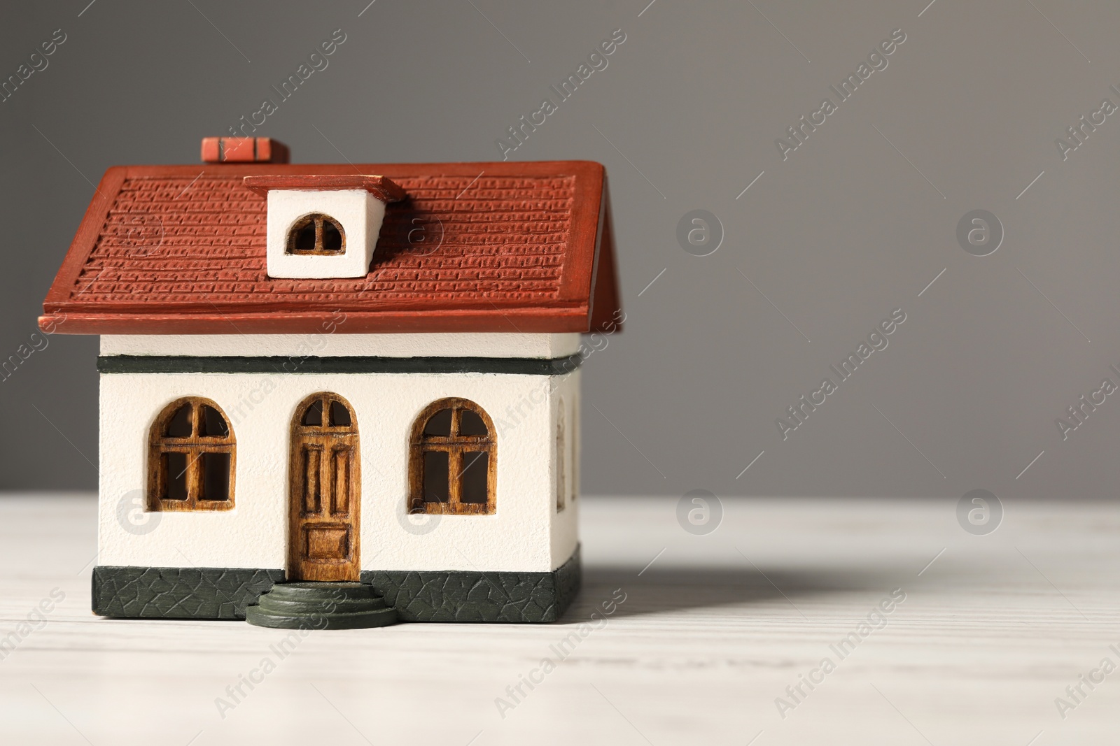 Photo of Mortgage concept. House model on white wooden table against grey background, space for text