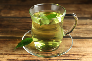 Photo of Cup of aromatic green tea on wooden table