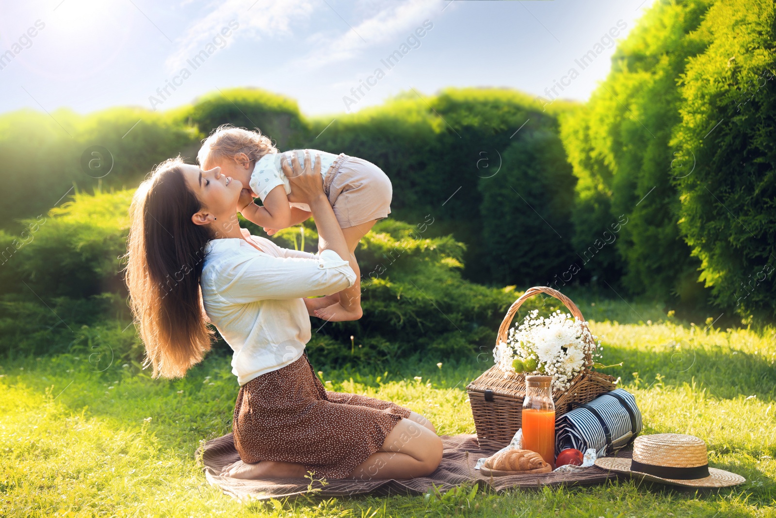 Photo of Mother and her baby daughter playing while having picnic in garden on sunny day