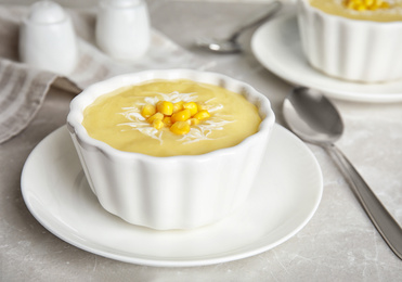 Photo of Delicious corn cream soup served on grey marble table