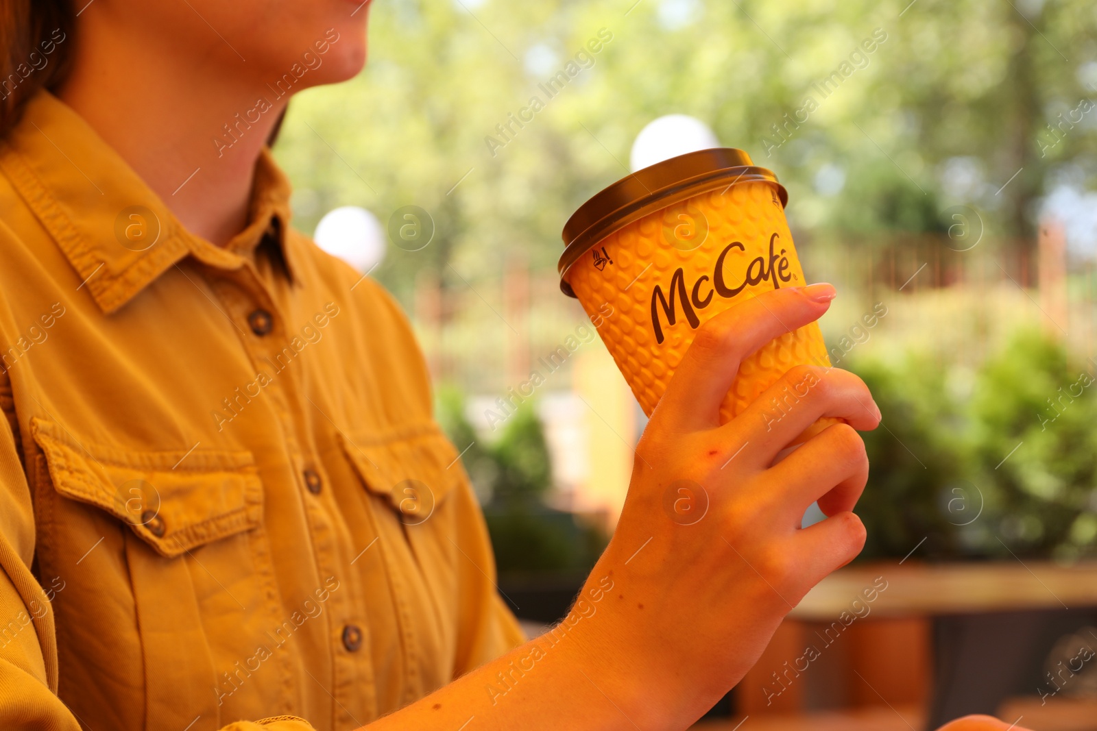 Photo of MYKOLAIV, UKRAINE - AUGUST 11, 2021: Woman with hot McDonald's drink in outdoor cafe, closeup