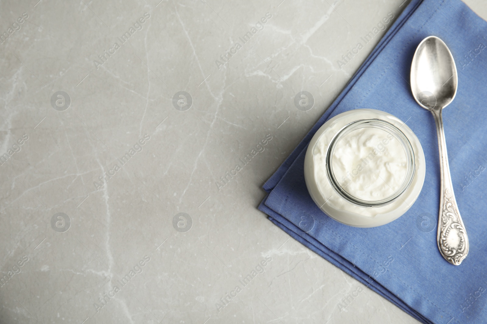 Photo of Tasty organic yogurt on grey marble table, top view. Space for text