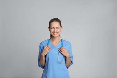 Portrait of young medical assistant with stethoscope on color background