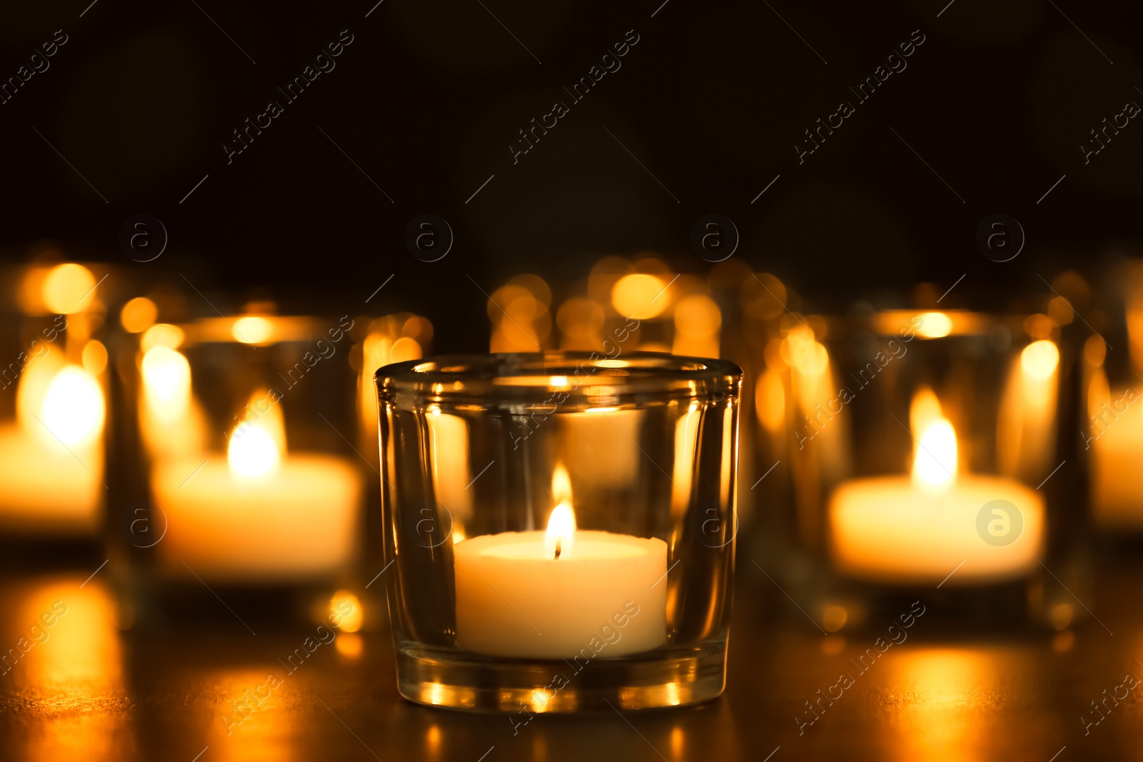 Photo of Burning candles on table in darkness. Funeral symbol