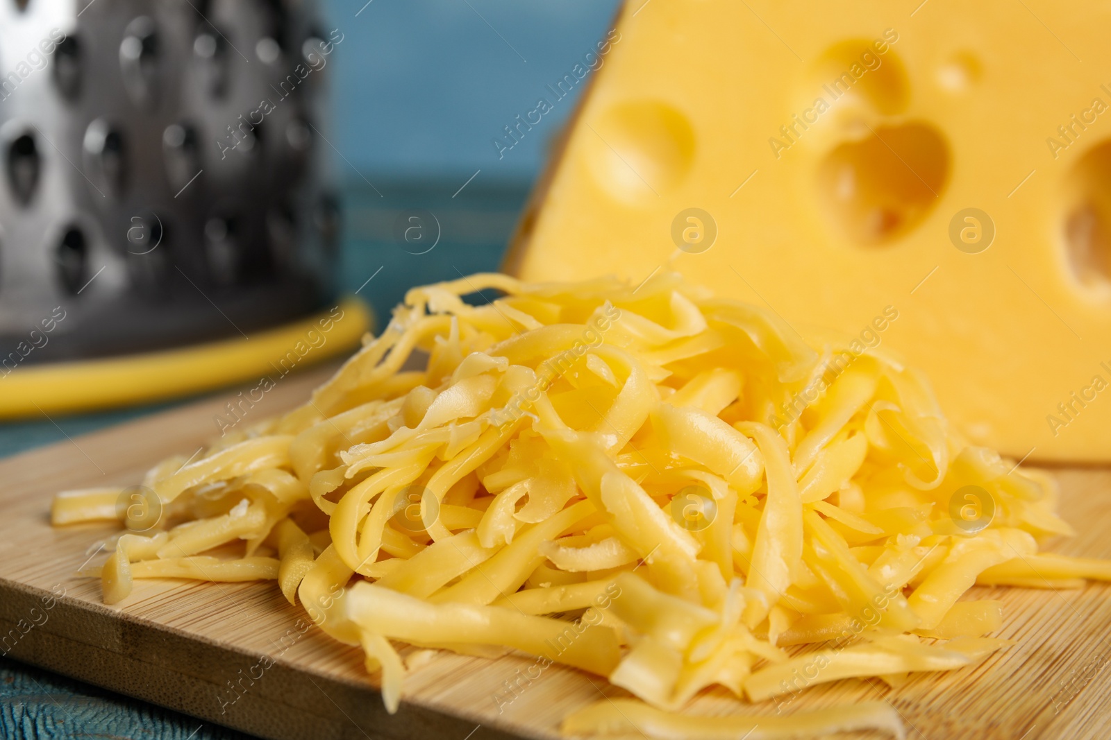 Photo of Tasty grated cheese on wooden table, closeup