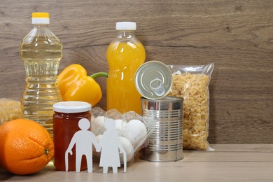 Photo of Humanitarian aid for elderly people. Different donation food and figures of senior couple on wooden table