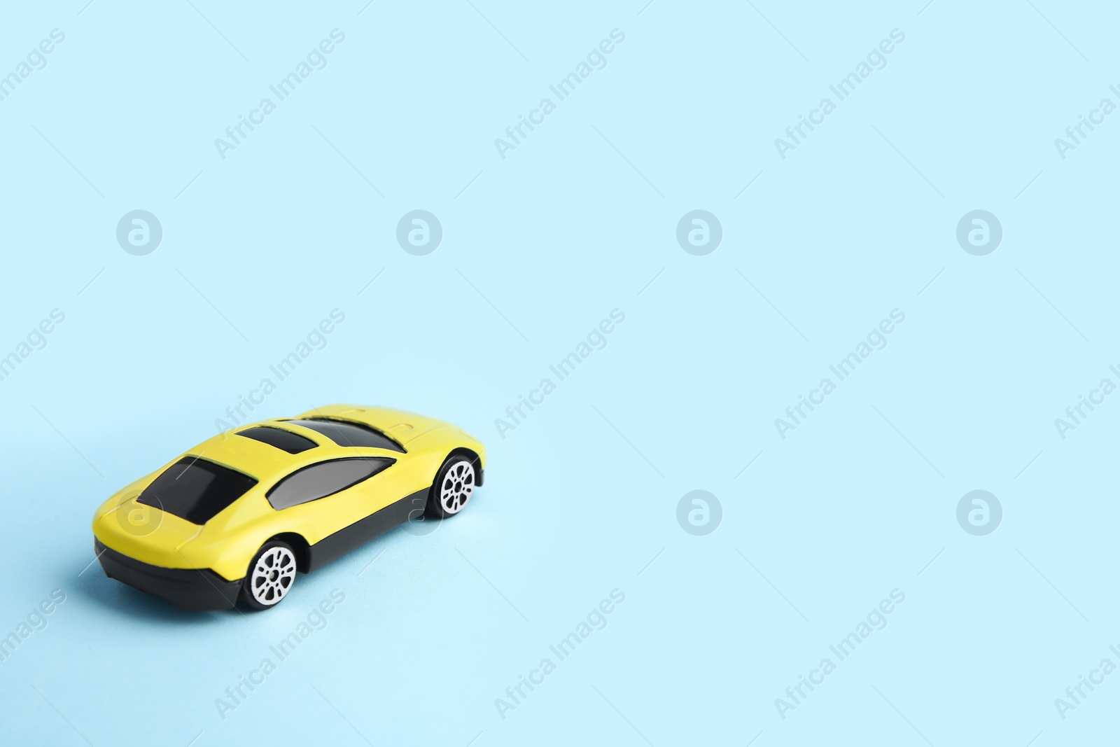 Photo of One yellow car on light blue background, space for text. Children`s toy