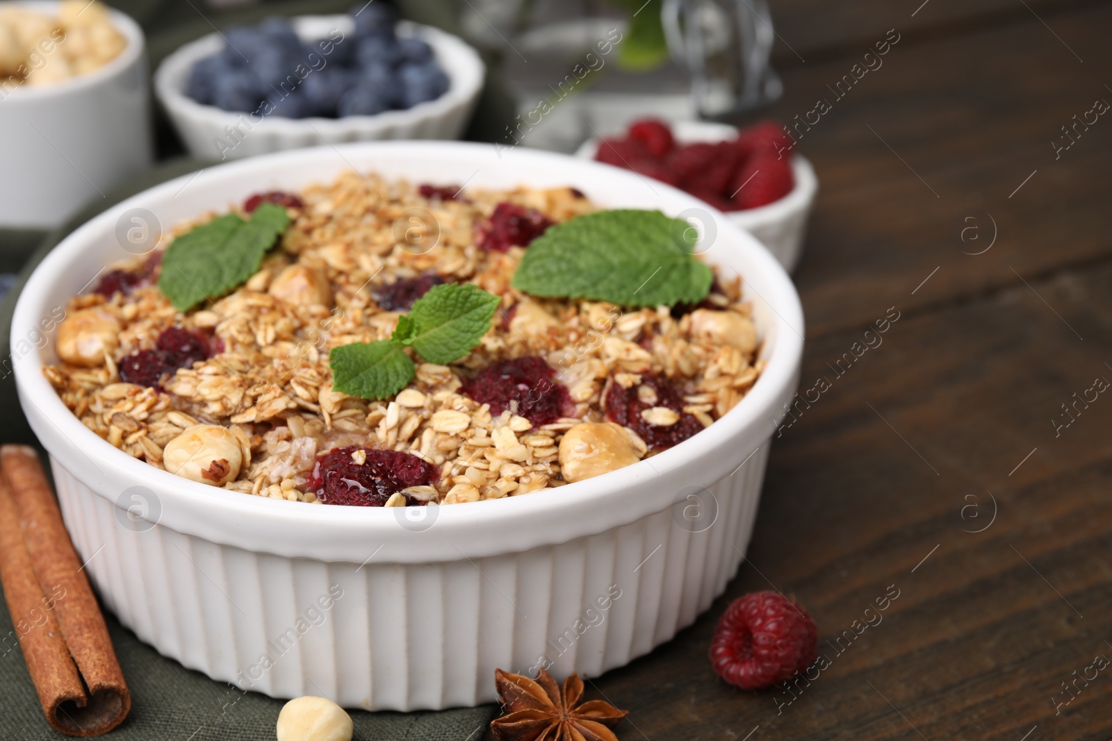 Photo of Tasty baked oatmeal with berries and nuts on wooden table, closeup