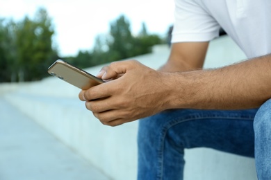 Photo of Man using modern mobile phone outdoors, closeup