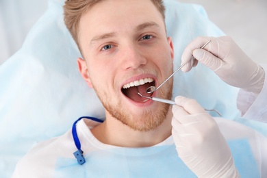 Photo of Dentist examining patient's teeth in modern clinic