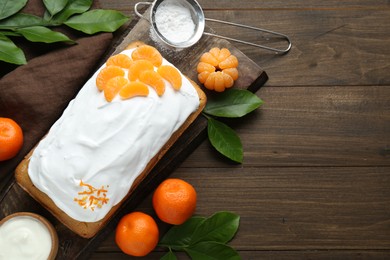 Delicious homemade yogurt cake with tangerines and cream on wooden table, flat lay. Space for text