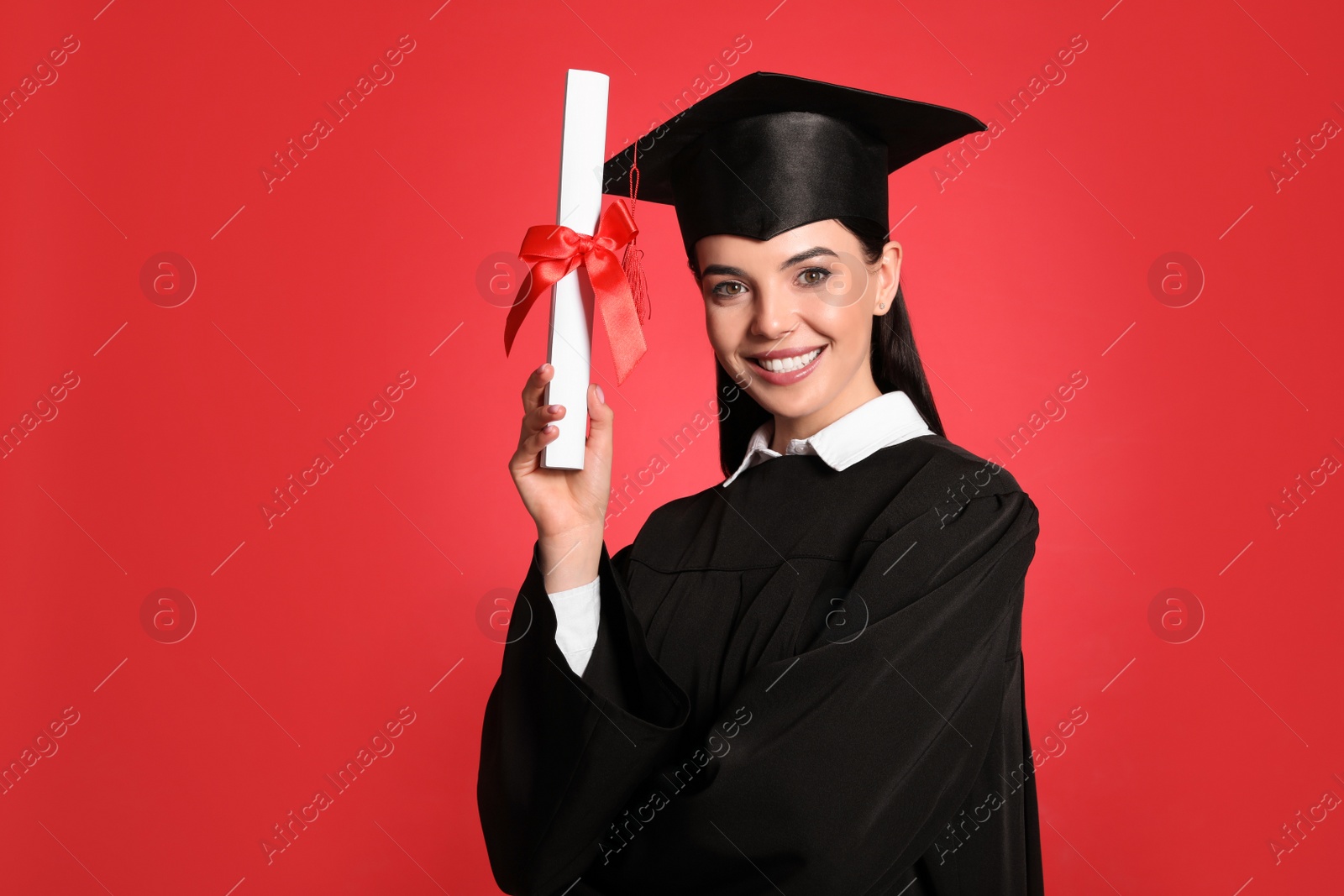 Photo of Happy student with graduation hat and diploma on red background. Space for text