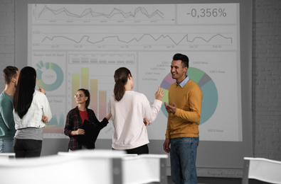 Photo of Young people having business training in conference room with projection screen