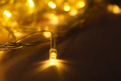 Photo of Glowing Christmas lights on violet background, closeup