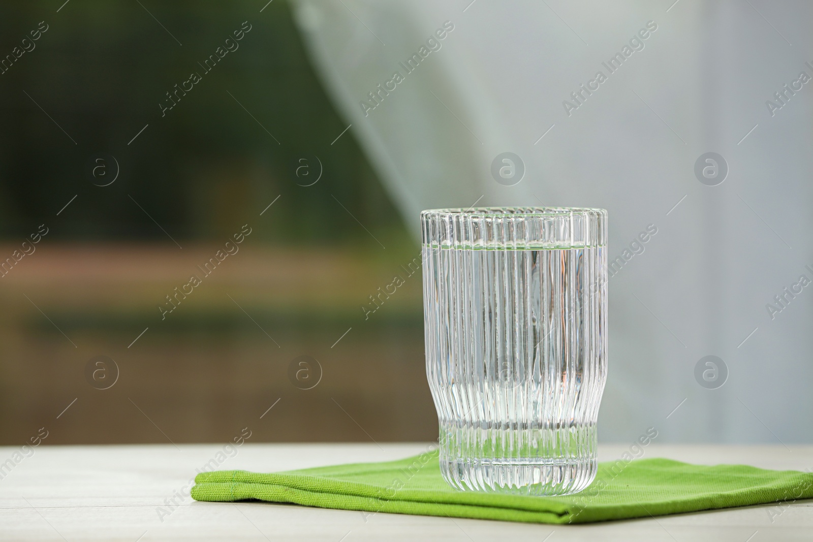 Photo of Glass of pure water on white table, space for text