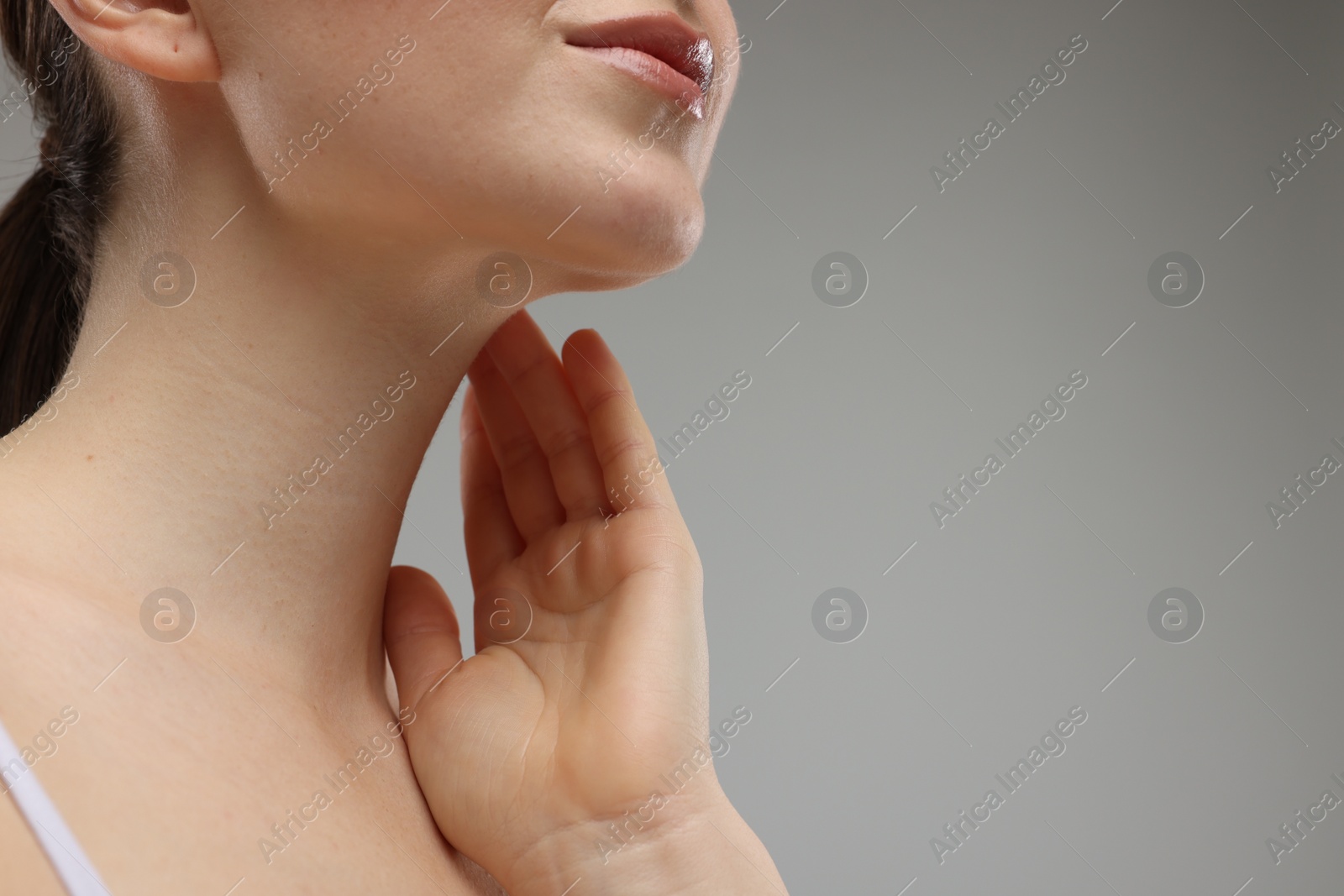 Photo of Woman touching her neck on grey background, closeup. Space for text