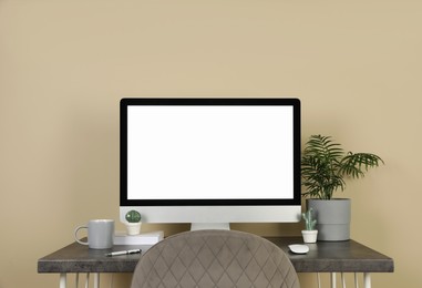 Photo of Modern computer, decor and office supplies on wooden table near beige wall