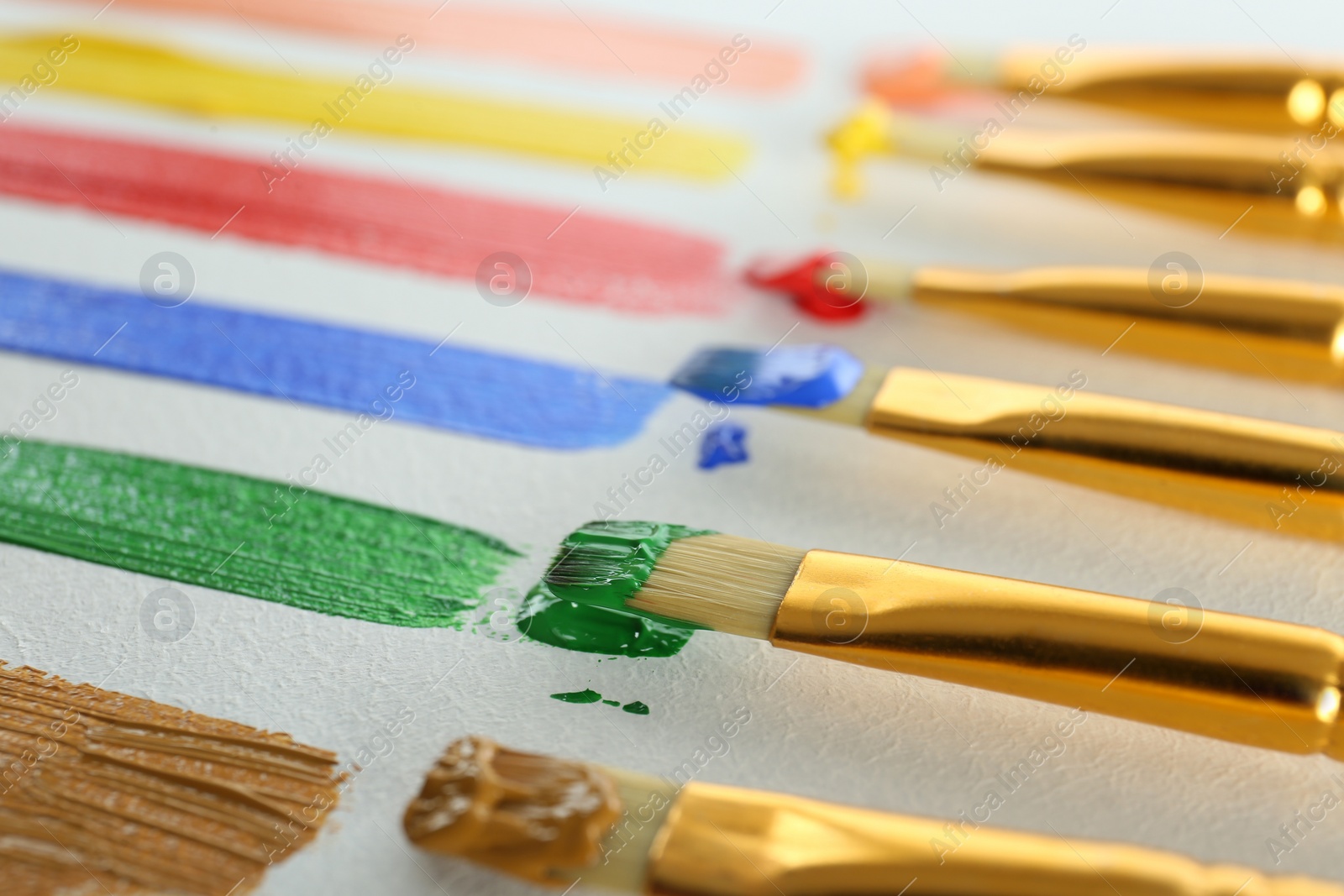 Photo of Brushes with bright paints on white background, closeup