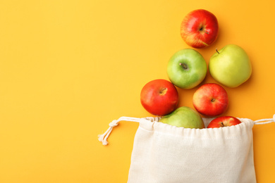 Cotton eco bag and apples on yellow background, flat lay. Space for text