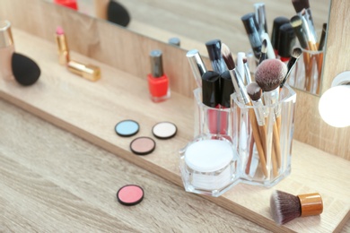 Photo of Organizer with cosmetic products for makeup on table near mirror