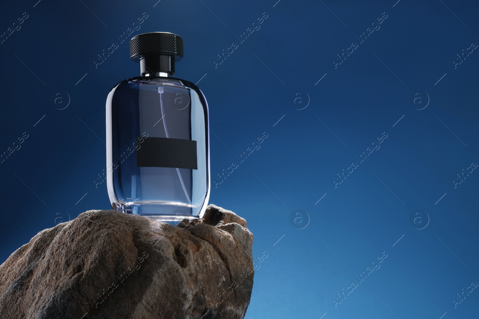 Photo of Stylish presentation of luxury men`s perfume on stone against light blue background. Space for text