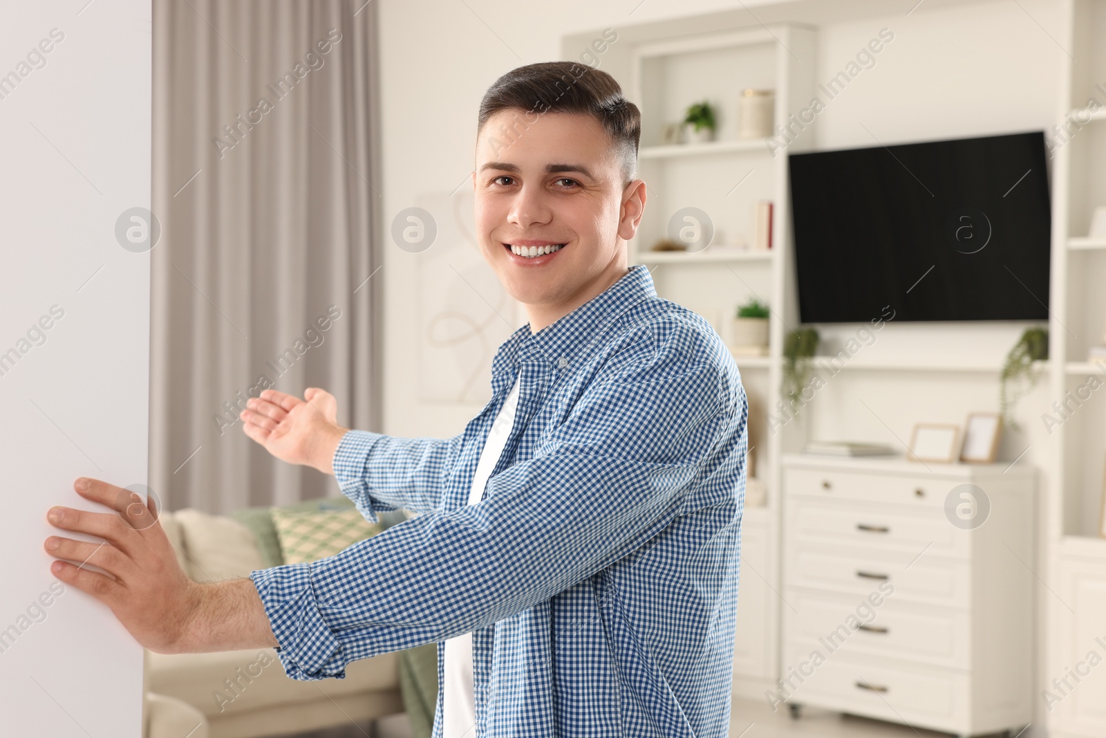 Photo of Handsome man inviting to come in room at home