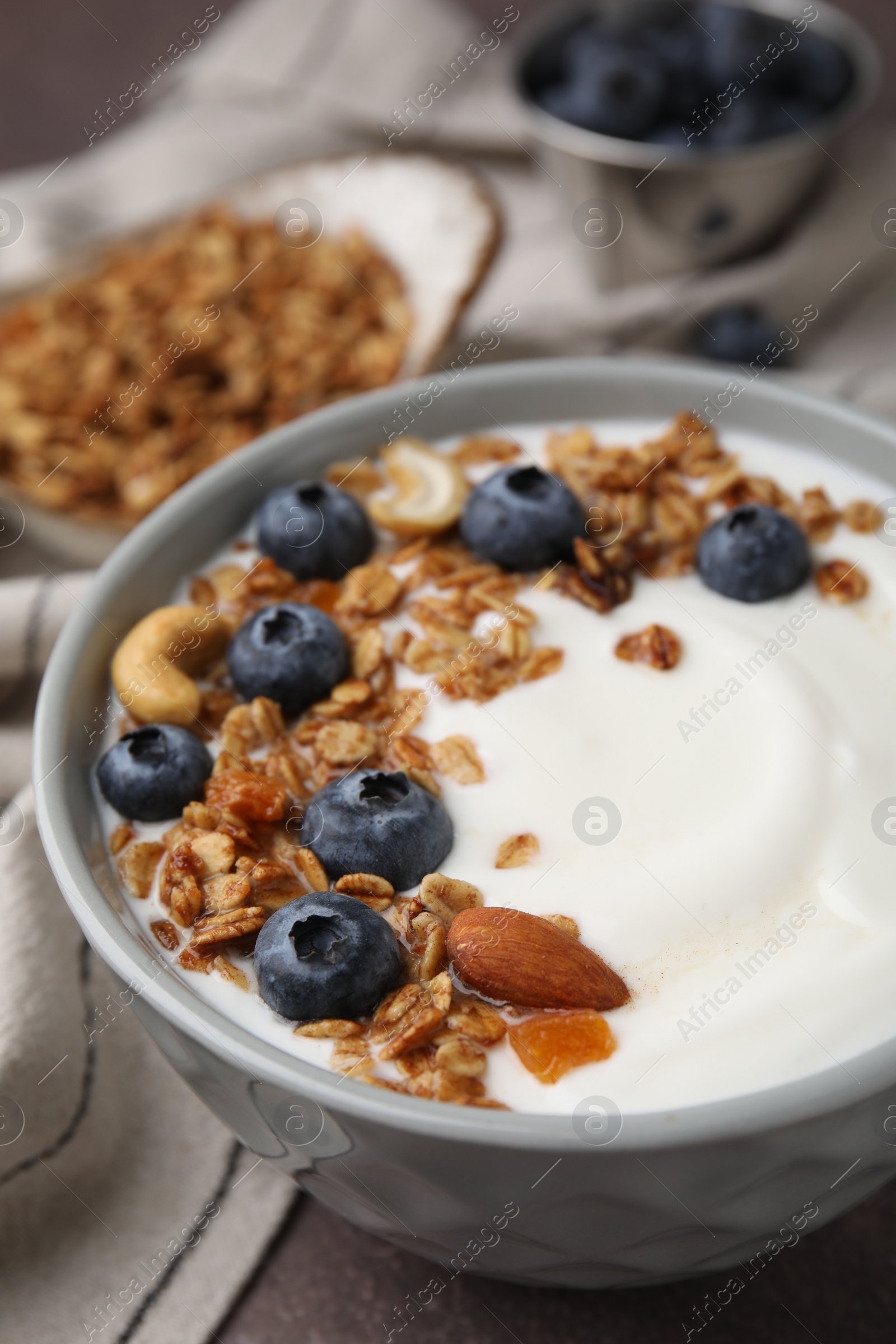 Photo of Bowl with yogurt, blueberries and granola on grey table, closeup